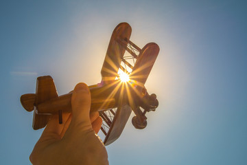 The hand with a wood plane on the background of the bright sun