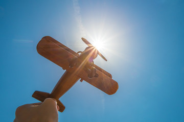 The hand hold a wood plane on the background of the sun