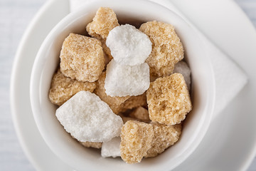 White sugar and brown sugar cane cube in white bowl on white background. Close up image