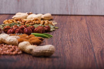 Assorted nuts on wooden surface. peanuts, almonds, hazelnuts, pumpkin seeds, walnuts, rice, buckwheat. Top view with copy space.