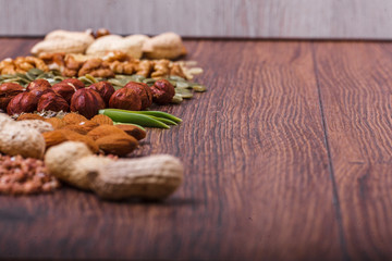 Assorted nuts on wooden surface. peanuts, almonds, hazelnuts, pumpkin seeds, walnuts, rice, buckwheat. Top view with copy space.