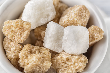White sugar and brown sugar cane cube in white bowl on white background. Close up image