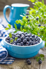 Fresh blueberries with leaves on wooden background