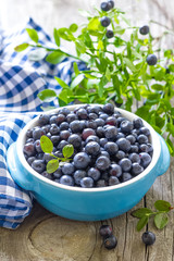 Fresh blueberries with leaves on wooden background