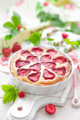 Delicious strawberry tart or cheesecake with fresh berries and cream cheese, closeup on white wooden rustic background