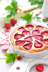 Delicious strawberry tart or cheesecake with fresh berries and cream cheese, closeup on white wooden rustic background