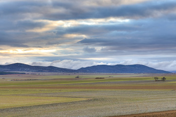 Contrastes en los campos de cultivo con montañas y nubes al fondo