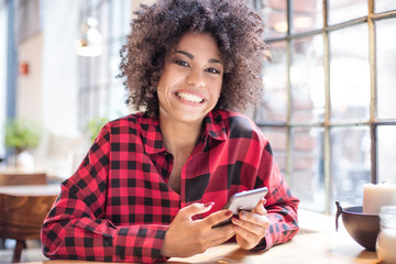Young girl with afro using smart phone.