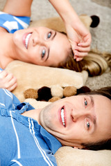 Happy couple lying on pillows on the floor