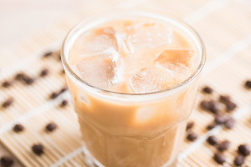 Glass of ice coffee with coffee bean on wooden background
