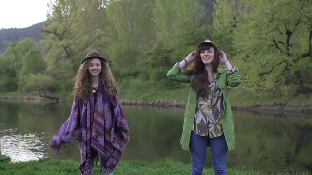 happy hipster girls among nature jumping and throwing their hats