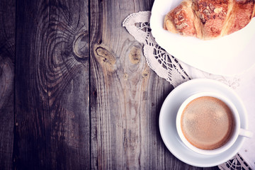 cup of coffee and a croissant on a saucer
