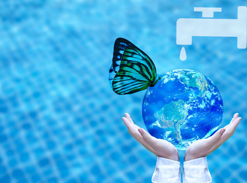 Butterfly drinking water from blue globe on hand.  Saving water concept, Element of image furnished by NASA