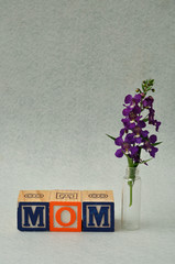 Mom spelled with alphabet blocks and small purple flowers