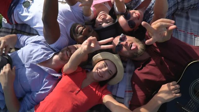A group of people lay their heads to each other on a picnic and shows a sign of peace