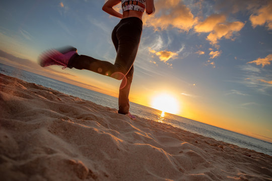 Running girl jogging at beachside at sunset time. Motion blurred image