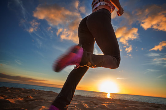 Running girl jogging at beachside at sunset time. Motion blurred image