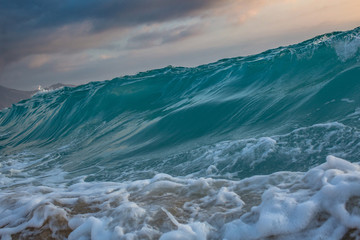 Sea wave rising. Ocean shorebreak at sunset time.