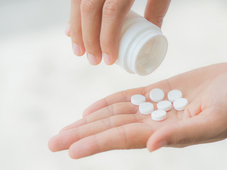 A young woman pours out medicine into her hand