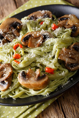 Green spinach pasta with mushrooms and parmesan cheese close-up. vertical