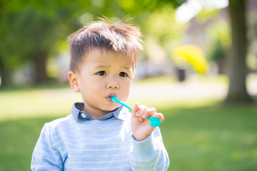 Asian baby uses toothbrush in the park, summer time