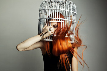 Beautiful redhead woman with birdcage 