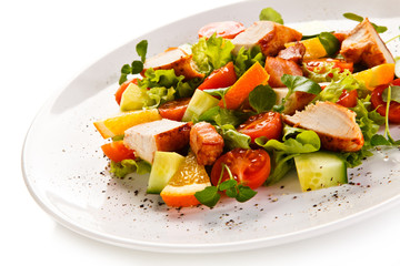 Grilled chicken fillet with vegetables salad on white background