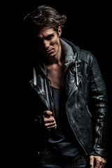 young biker in leather jacket pulling his collar