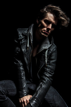 relaxed dramatic man in leather jacket sits and looks away