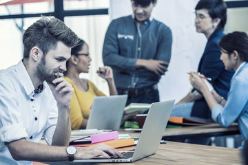 Businessman working in happy action with computer over the photo blurred of Group Of Asian and Multiethnic Business people with casual suit in the modern Office, people business group concept