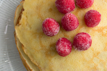 Stack of wheat golden pancakes or pancake cake with freshly picked raspberry
