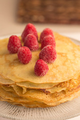 Stack of wheat golden pancakes or pancake cake with freshly picked raspberry