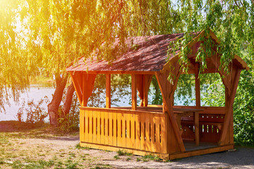 gazebo for family entertainment and is made of wood, stands on the shore of the lake