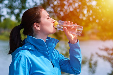 beautiful young girl outdoors drinking pure water