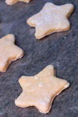 Cookie dough in different shapes lies on the baking sheet.