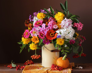 country flowers in can on the table, pumpkin and berries.