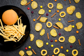 Fast food: top view of burger, french fries, chips, rings and candies. Unhealthy eating concept
