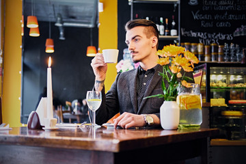 A man drinks coffee in a cafe.