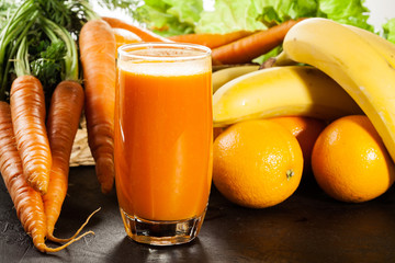 Glass of fruit juice with orange, carrots and banana