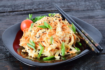 Korean traditional kitchen. Raw marinated chicken in soy sauce, spices, onions and carrots on a black plate on a dark background. Healthy food. Healthy eating concept