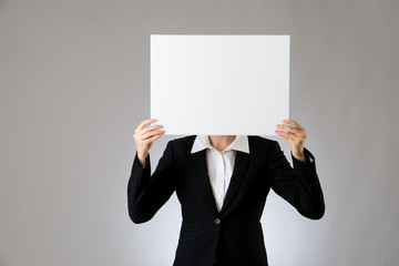 Young woman holding white card over face