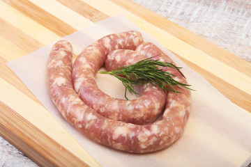 Homemade Raw sausage with spices on a wooden background.