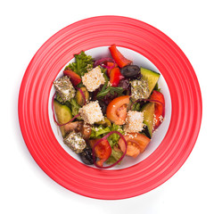 Greek salad with vegetables and feta in red dish