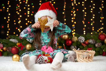child girl portrait in christmas decoration, happy emotions, winter holiday concept, dark background with illumination and boke lights