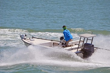 Small sport fishing skiff powered by a single outboard engine speeding on the florida intra-coastal...