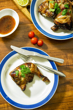 Grilled chicken thight on white plate with wood table background