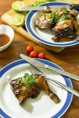 Grilled chicken thight on white plate with wood table background