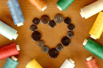 Sewing accessories: buttons in form of a heart and colorful spools of thread