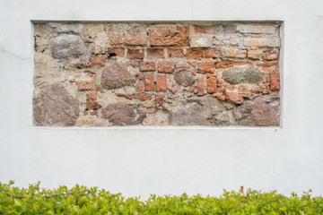 Old stone wall fragment in white plastered wall as background