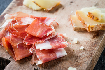 Spanish ham jamon serrano or Italian prosciutto crudo and sliced Italian hard cheese pecorino toscano on old wooden board - obrazy, fototapety, plakaty